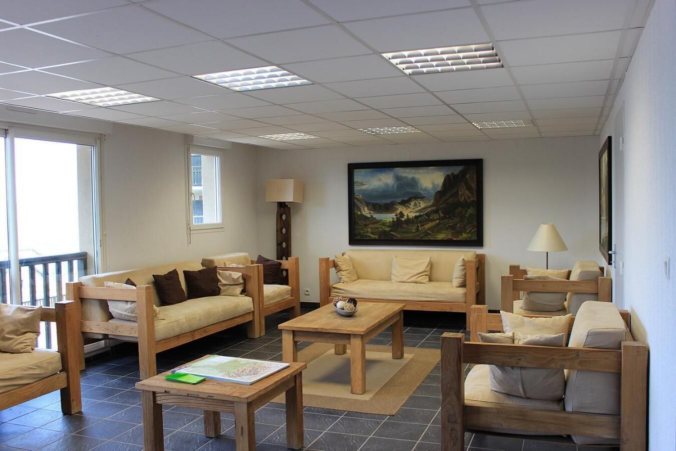 A spacious living room with a large painting, wooden furniture, and a view of the outdoors.