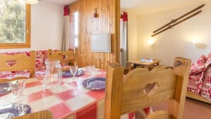 Un comedor con mantel a cuadros, sillas de madera con forma de corazón y un soporte para esquíes en la pared.
