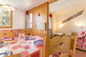 Een eethoek met een geruit tafelkleed, houten stoelen met hartjes en een ski-rek aan de muur.