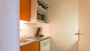 Una cocina compacta con lavamanos, hervidor y lavavajillas.