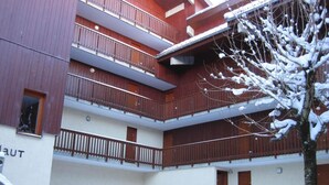 Un edificio de varios pisos con balcones y suelo cubierto de nieve.