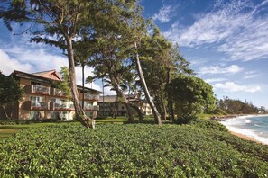 A beachfront hotel with multiple balconies, a well-maintained lawn, and a view of the ocean. - 1 BedRm Suite at Kapa'a Oceanfront Resort (Kapaʻa)