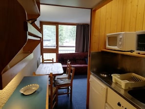A compact kitchen with a microwave, sink, and dining area.