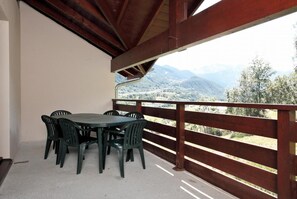 Un balcon avec une table et des chaises, donnant sur un paysage montagneux.