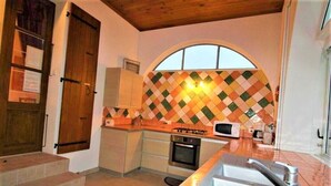 A kitchen with a tiled backsplash, a stove, oven, and a sink. - Vacation rental for 2–4 people, 1 bedroom, 1 shower room, heated outdoor pool, garden, trampoline (Ardèche)
