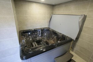 Relax in a spacious hot tub with multiple jets, set against a wall in a minimalist bathroom.