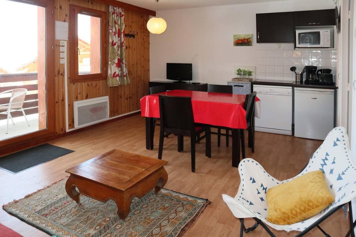 A compact living space with a dining area, kitchen, and a small seating area with a chair and a table.