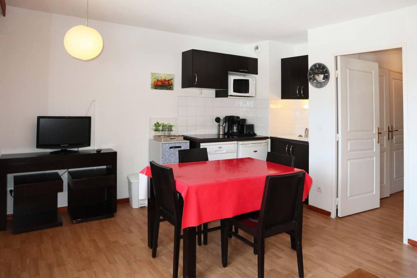 A compact kitchen with a dining table, chairs, a microwave, and a television.