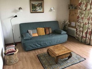 A living room with a sofa, a wooden coffee table, a floor lamp, and a patterned rug.