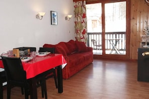 A dining area with a red tablecloth, a red sofa, and a wooden floor.