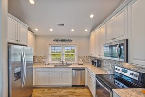 A modern kitchen with stainless steel appliances, a double sink, and a large window.