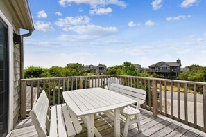 A wooden deck with a white table and bench, surrounded by a wooden railing, overlooking a residential area. - Bridger has done some décor renos. Come see ! (Duck)