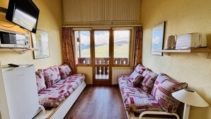 Ein gemütliches Zimmer mit einer Sofaecke, einem Fernseher, einer Mikrowelle und einem Kühlschrank.