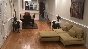 A spacious living area with a wooden floor, a beige sectional sofa, a dining table with chairs, and a staircase leading to another level. - Bloomingdale Beauty in NW DC 9 blocks from Union Station, near RED LINE/NOMA (Washington)