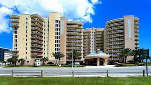 Un hôtel à plusieurs étages doté de balcons, d’un atrium central et de palmiers.