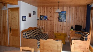 Una cabaña de madera acogedora con un sofá, un sillón amarillo y un televisor.
