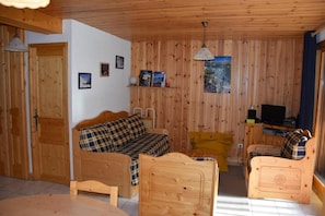 Una cabaña de madera acogedora con un sofá, un sillón amarillo y un televisor.