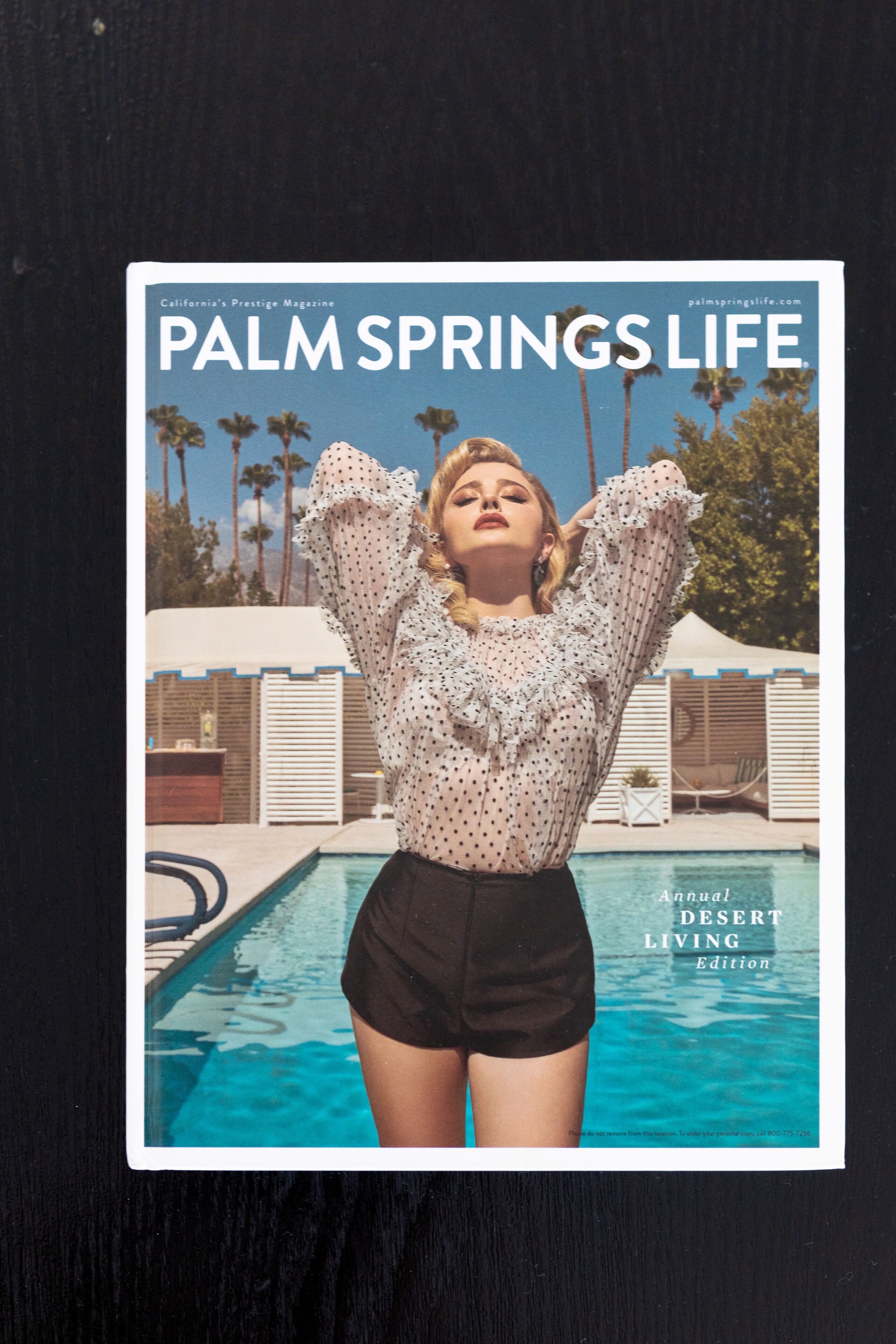 Une couverture de magazine intitulée « Palm Springs Life », avec une piscine et des palmiers en arrière-plan.