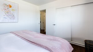 A bedroom with a bed, a pink blanket, a map on the wall, and a wardrobe.