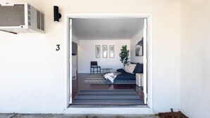 A modern interior with a sofa, a small table, and a chair. There is a door leading to another room and a number '3' on the wall.