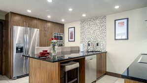 A modern kitchen with wooden cabinets, stainless steel appliances, a central island with seating, and tiled backsplash. - Walk to Thunderhead Lift! Hot Tub/ Pool! Quiet Building! (Steamboat Springs)