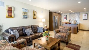 A modern living room with a sofa, armchairs, a coffee table, and a kitchen area with a refrigerator and microwave. - Walk to Thunderhead Lift! Hot Tub/ Pool! Quiet Building! (Steamboat Springs)