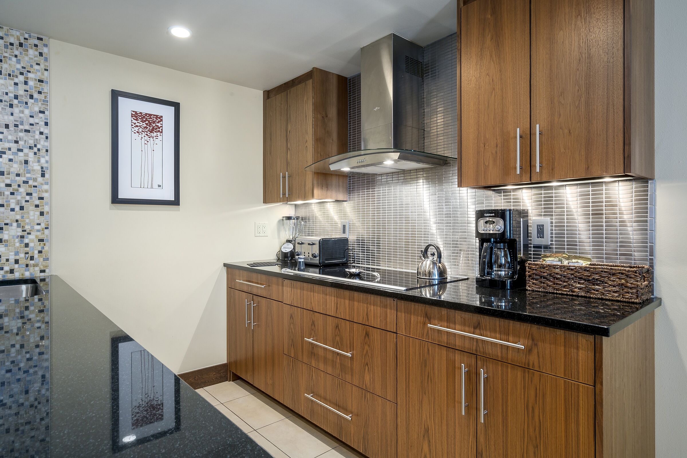 Una cocina moderna con armarios de madera, encimera negra y electrodomésticos de acero inoxidable.