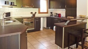 Een moderne keuken met donkere kastjes, een roestvrijstalen spoelbak en een ingebouwde oven.