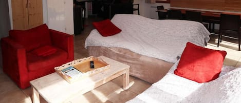 Una sala acogedora con un sofá, un sillón rojo y una mesita de centro.