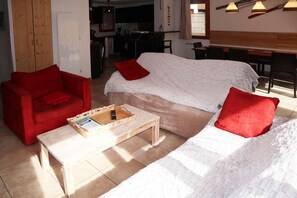 A cozy living area with a sofa, a red armchair, and a coffee table. - Chalet, ski-in/ski-out & foot of the slopes, swimming pool, sauna, hammam, terrace (Les Orres)