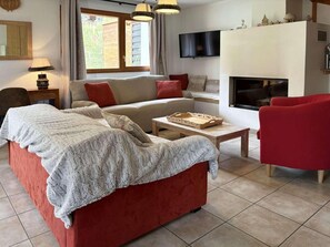 A living room with a red sofa, a beige sofa, a red armchair, a wooden coffee table, and a fireplace. - Chalet, ski-in/ski-out & foot of the slopes, swimming pool, sauna, hammam, terrace (Les Orres)