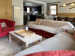 A living room with a red sofa, a beige sofa, and a wooden coffee table with a tray. - Chalet, ski-in/ski-out & foot of the slopes, swimming pool, sauna, hammam, terrace (Les Orres)