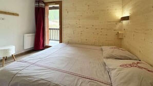 Een slaapkamer met een groot bed, houten wanden, een bedlampje en uitzicht door een open deur.