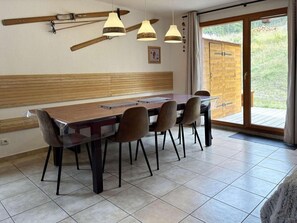 A dining area with a wooden table and chairs, pendant lights, and a view of the outdoors. - Chalet, ski-in/ski-out & foot of the slopes, swimming pool, sauna, hammam, terrace (Les Orres)