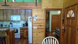 A cozy cabin-style kitchen with wooden walls, a dining table, and a refrigerator. - Cozy and comfortable wooded cabin (Alta)