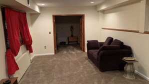 A living room with a beige carpet, a dark-colored sofa, and a small side table.