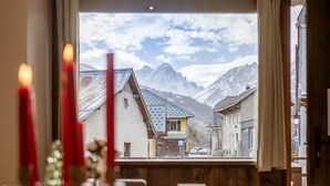 Une table à manger décorée de bougies, de verres et d’objets d’ornement, avec une vue sur les montagnes par la fenêtre.