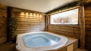 Une cabane en bois avec un jacuzzi dans un coin, une fenêtre donnant sur les arbres et une plante en pot.