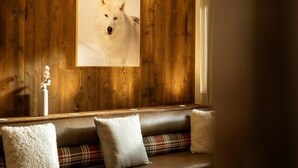 Un salon chaleureux avec un mur en bois, un canapé agrémenté de coussins à carreaux et un tableau encadré représentant un chien.