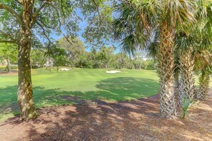 Un parcours de golf avec des bunkers de sable, des arbres et un ciel dégagé.