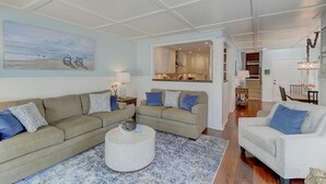 A spacious living room with a large sectional sofa, a round coffee table, and a dining area with a table and chairs. - Golf View, Pool, Pickleball, Stocked kitchen - 52 Fairway Dunes (Isle Of Palms)