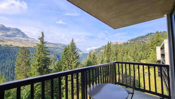 A balcony with a table and chairs, overlooking a mountainous landscape with dense forests and a clear sky. - 150m from ski lifts, 3rd floor, balcony, tv, ski locker, 60m², Flaine (Flaine)