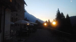 Un restaurant avec une terrasse, des tables et des parasols, offrant une vue sur une montagne.
