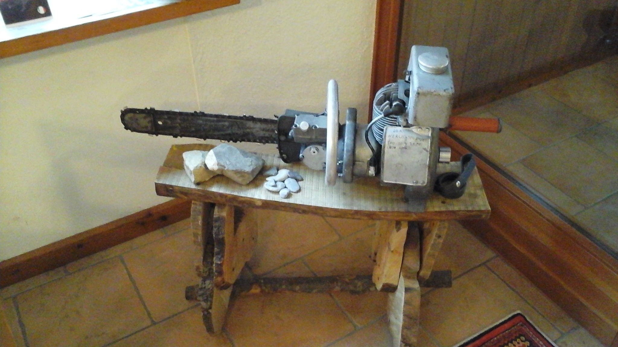 Un établi en bois avec une tronçonneuse et un outil électrique, probablement utilisé pour le travail du bois ou du métal.