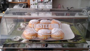 A display case with a selection of pastries, including donuts and a cake, with a visible brand name and a slogan.