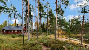 A cabin with a metal roof, surrounded by a forest and a small pond. - Kuusikumpu by Interhome (Petäjävesi)