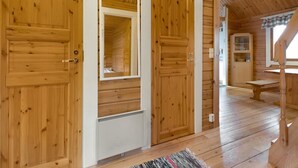 A wooden cabin interior with a large wooden door, a small window, and a wooden bench. - Kuusikumpu by Interhome (Petäjävesi)