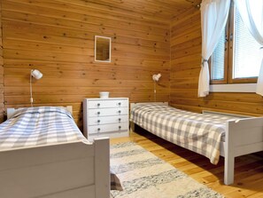 Ein Zimmer mit zwei Betten, einem Schminktisch und einem Fenster mit Vorhängen.