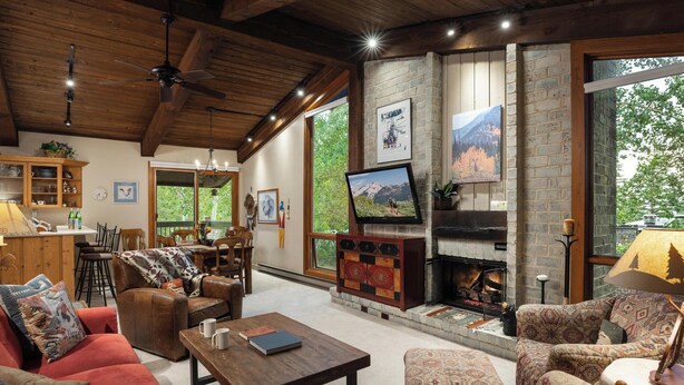 A cozy living room with a fireplace, comfortable seating, and a television. - Top of the Village - Summit 301 - Ski-in/Ski-out (Snowmass Village)