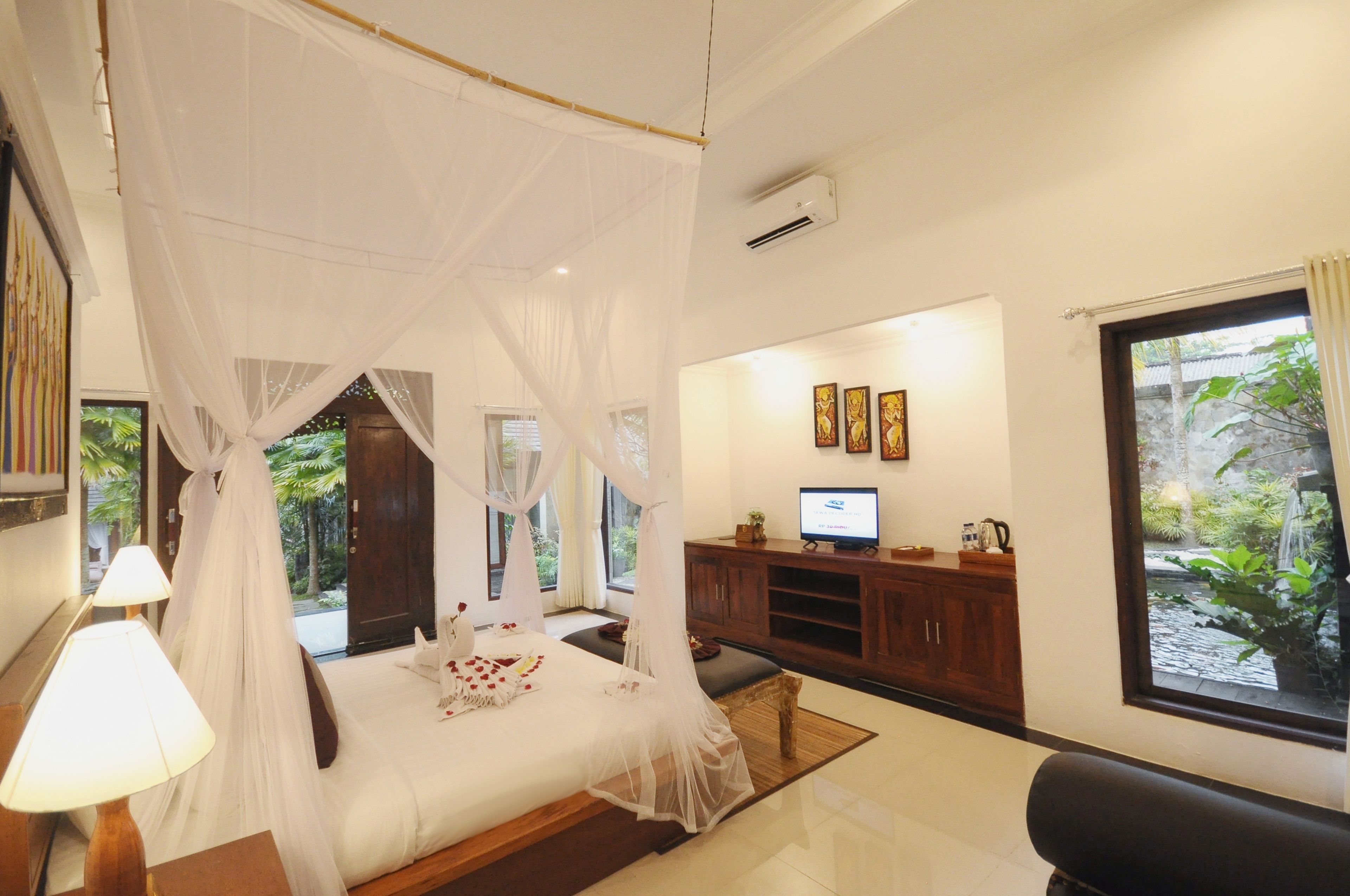 A bedroom with a canopy bed, a television, and a view of the garden.